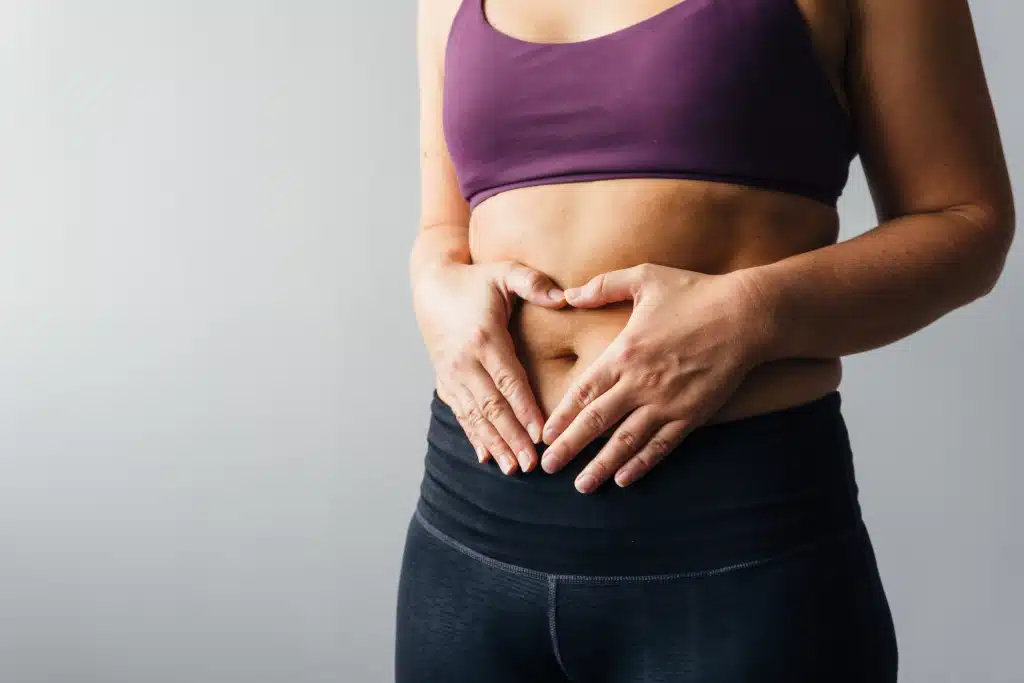 Frau in Sportbekleidung legt ihre Hände auf ihren Bauch