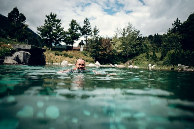 Mann schwimmt im Naturteich im BLEIB BERG