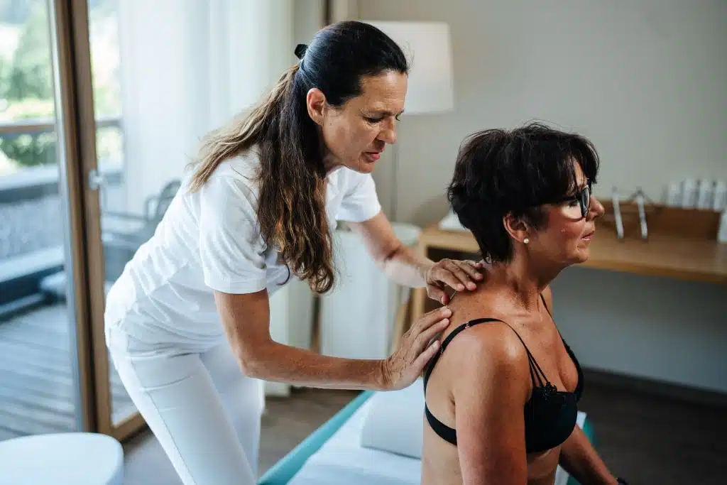 Ärztin untersucht den Rücken einer Patientin