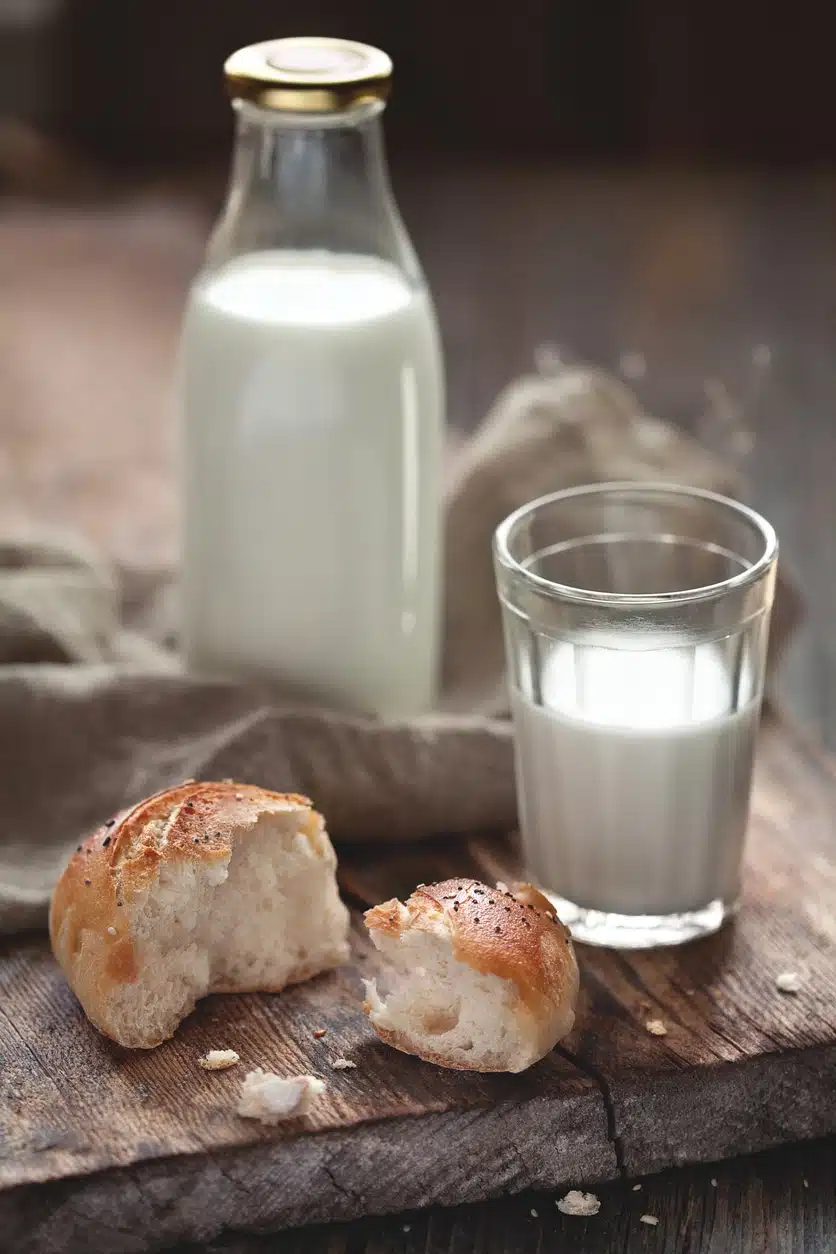 Eine Flasche und ein Glas voll Milch neben einer Semmel