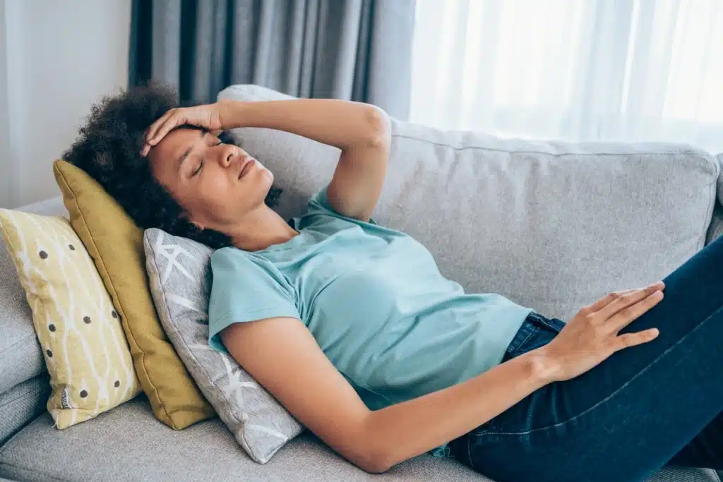 Frau mit Long-Covid liegt auf der Couch