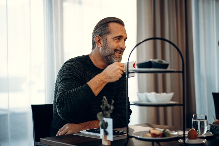 Mann trinkt beim Frühstück im BLEIB BERG Kaffee