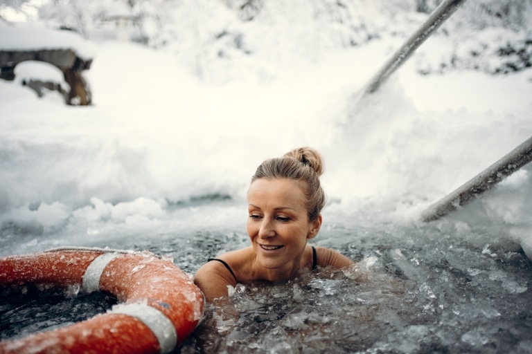 Frau ist bis zu den Schultern zugefrorenen Naturbadeteich zum Eisbaden