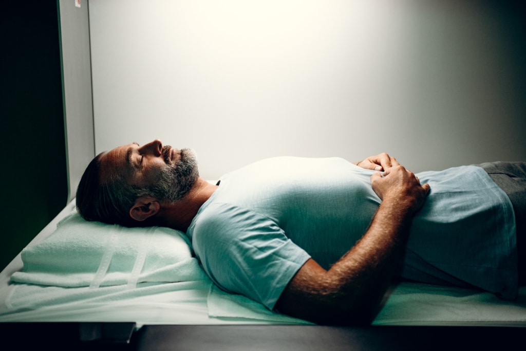 Mann liegt mit geschlossenen Augen auf Behandlungsbett