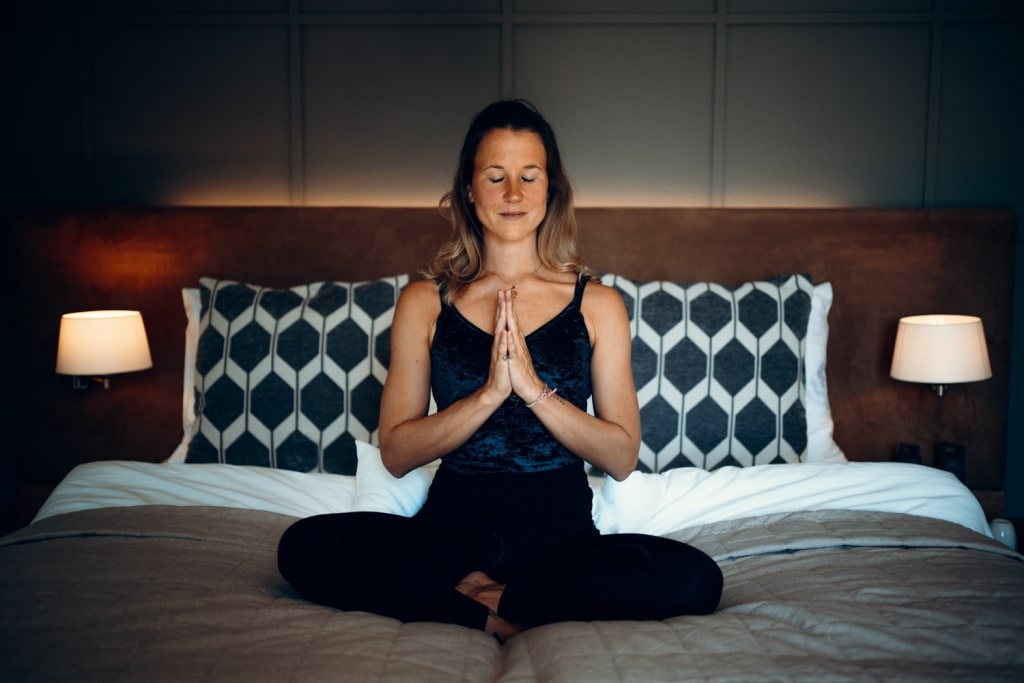 Yoga-Trainerin sitzt im Lotussitz im Bett